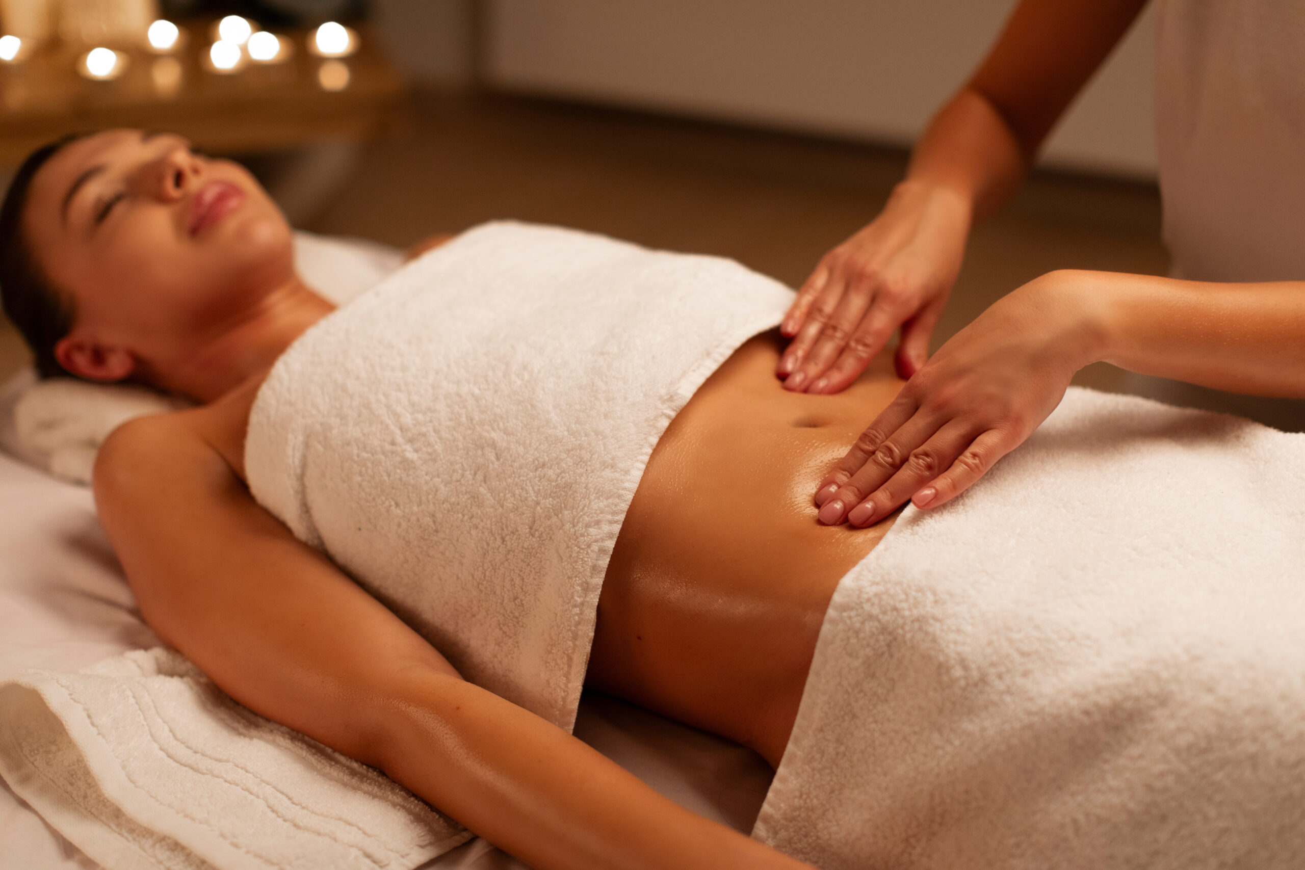 Professional masseur making relaxing massage of stomach for woman in calm spa center interior, woman doctor masseur during work with patient Salle de sport andernos